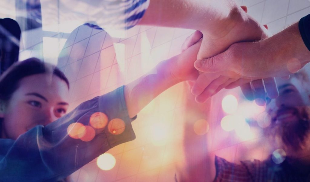 Group of hands coming together, symbolizing collaboration and teamwork, with a blurred background effect.